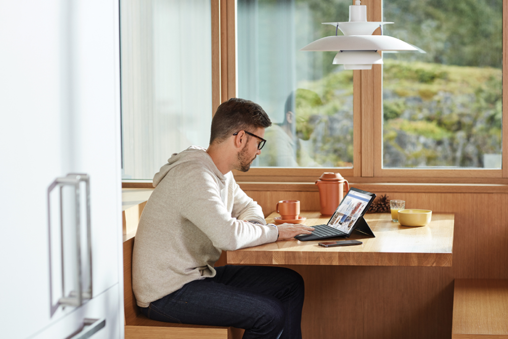 Adult male on the go works from home at breakfast table with Surface Pro 6