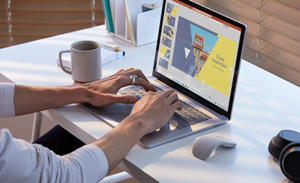 Photograph of worker on Surface Laptop 3 in PowerPoint with Surface Mouse and Surface Headphones.