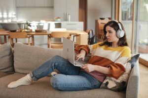 Female student with Surface Book 2 and Surface Headphones at home works remotely or attends Teams meeting.