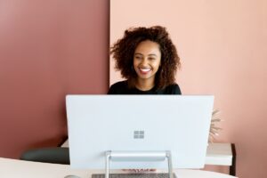 Smiling woman sitting behind a Microsoft-branded computer.