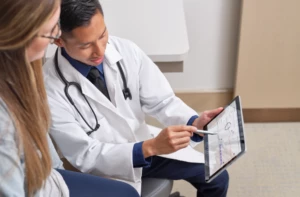 Doctor using mobile tablet to discuss treatment options with patient.
