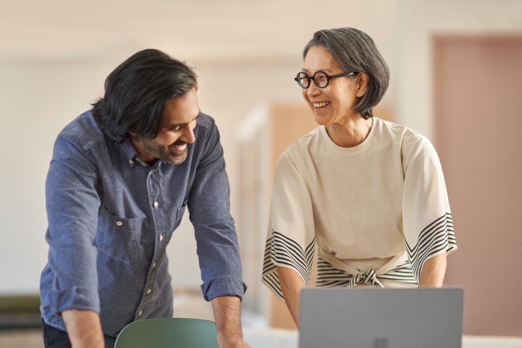 Two coworkers collaborating with a generative AI tool on a laptop computer.