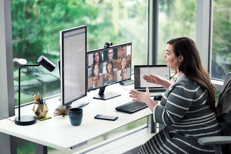 Female enterprise employee working at desk with multiple devices