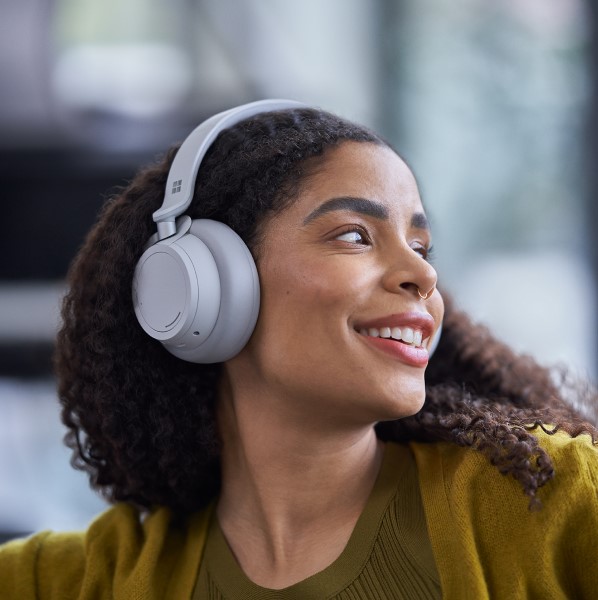 a person wearing headphones, looking to the side, smiling