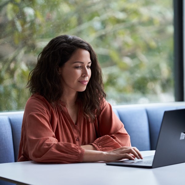 A person sitting in a booth at a table working on a laptop.