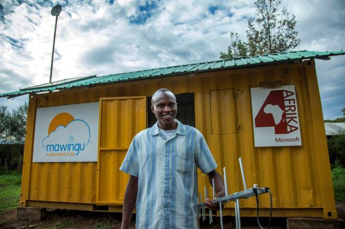 Benson Maina holds a TV white spaces antenna in front of the Mawingu White Spaces Broadband pilot container near Nanyuki, Kenya. The pilot offers the public access to Wi-Fi, devices and services free of charge. (Photo credit: Georgina Goodwin)