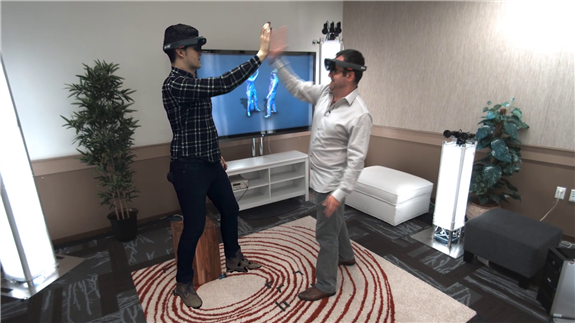 Holoportation - a man wearing a Hololens device giving a high-five to a 'hologram' man 