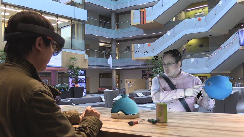 Two people using Holoportation across a desk in an atrium