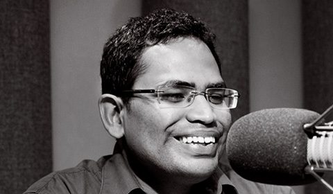 a man wearing glasses and smiling at the camera