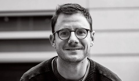 a man wearing glasses and smiling at the camera