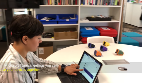 A woman is sat at a table looking at her laptop