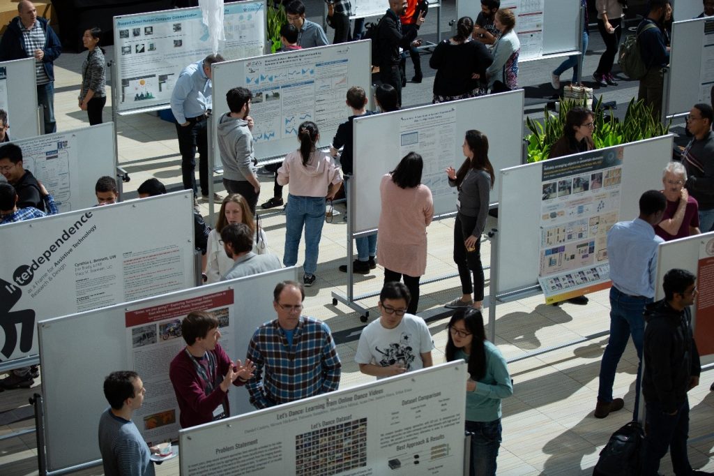 2018 PhD Summit Poster Session ,image of people viewing and engaing with the posters