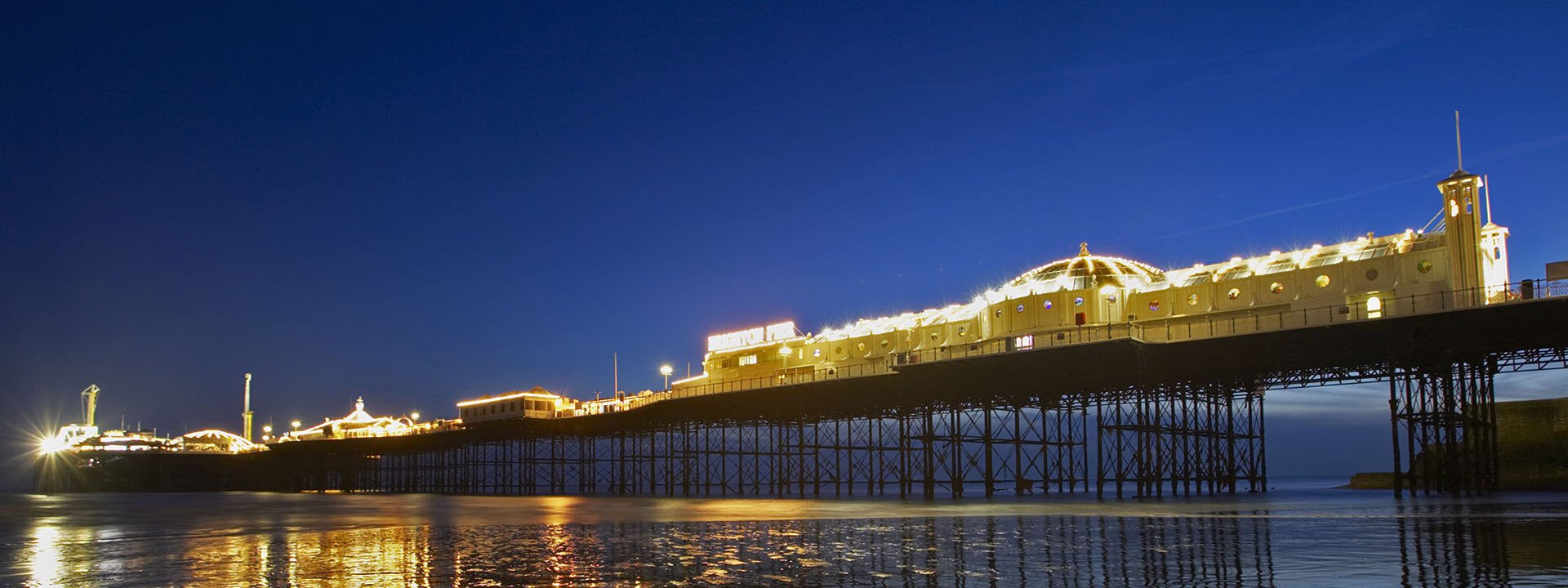 Photo of the Brighton (UK) pier at night reflected in the water