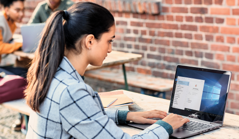 a woman using a laptop computer sitting on top of a building