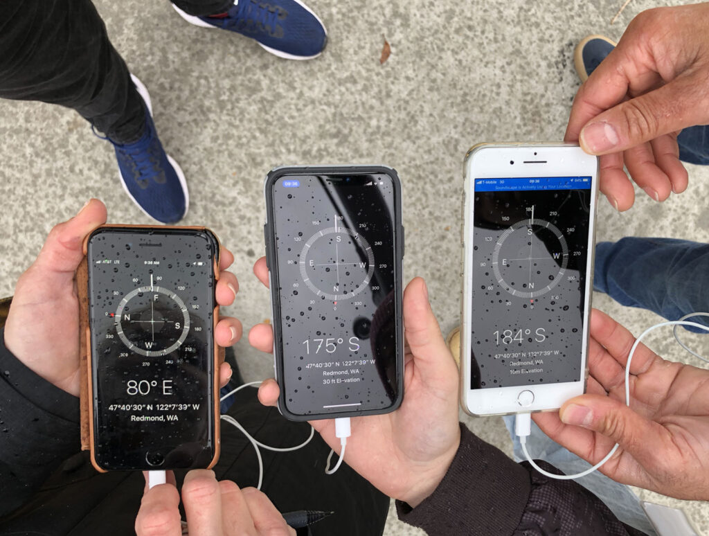 Three iPhones, open on the compass app, two reading south and one reading east