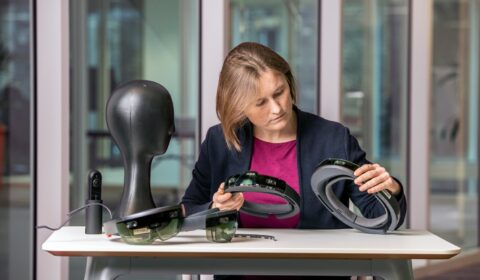 Cecily Morrison sitting at a table holding two HoloLens