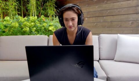 Ester Baiget sitting at a table with a laptop and smiling at the camera