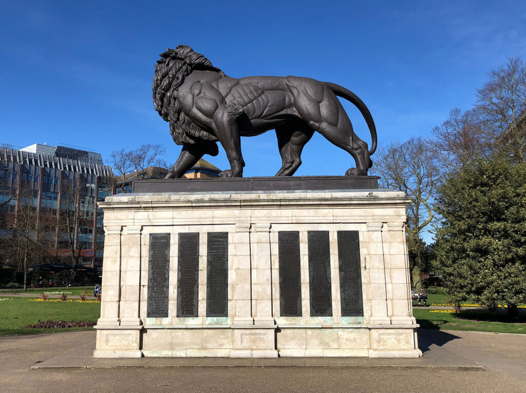 large statue of a lion stood on a plinth. The plinth has a list of names of. those who lost their life in the Battle of Maiwand