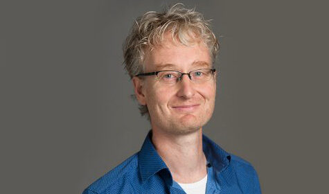 a man wearing glasses and smiling at the camera