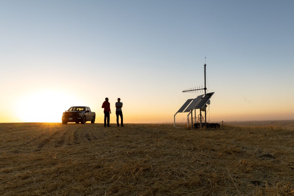 photo of people on horizon on a farm. The sun is setting.