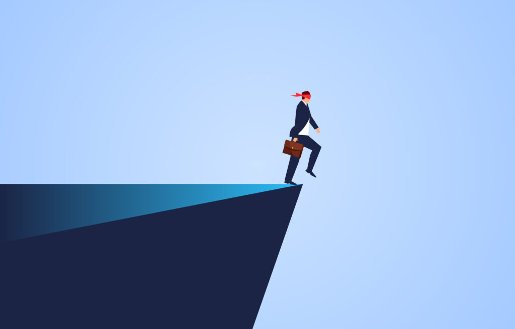 blindfolded businessman at edge of a cliff