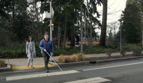 man using a cane on a crosswalk guided by Soundscape route audio beacons