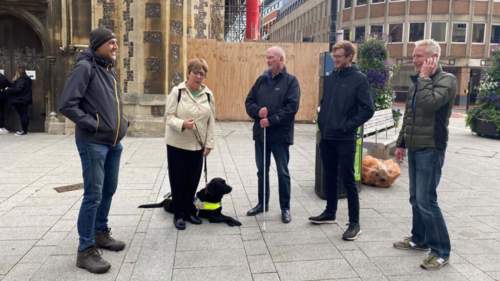 A group of people standing outside in an enclosed and paved area with buildings nearby