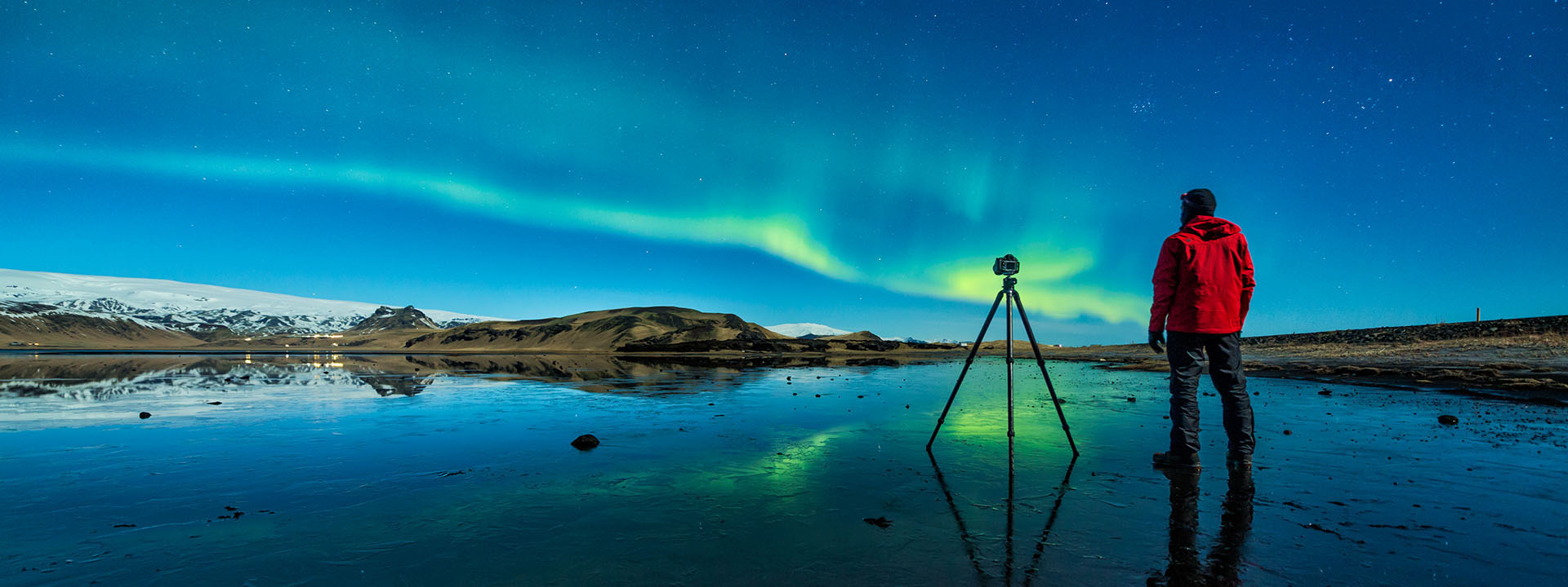 Climate Research Initiative - photo of a man with a tripod looking up at the Northern Lights
