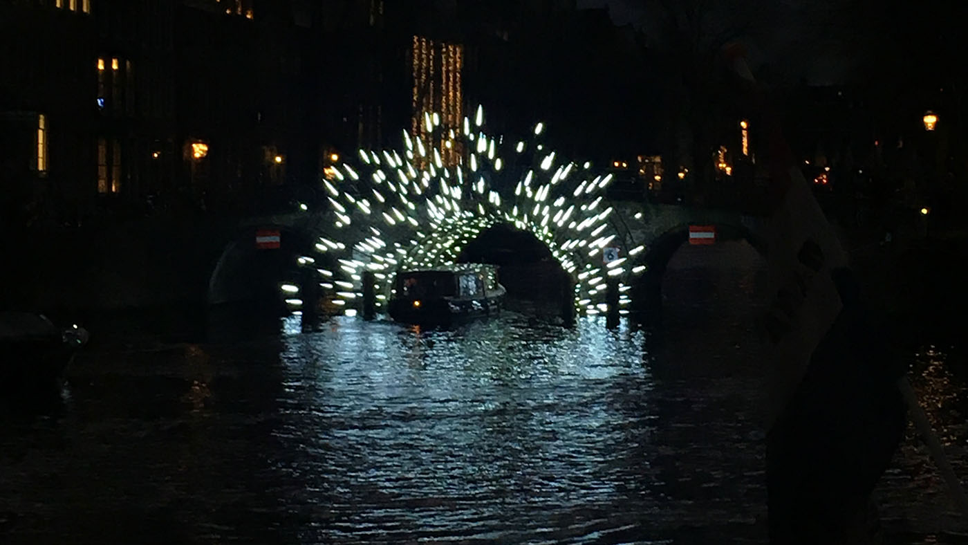 Soundscape - Amsterdam canal boat passing under a bridge which is illuminated with lights fanning out from under the tunnel