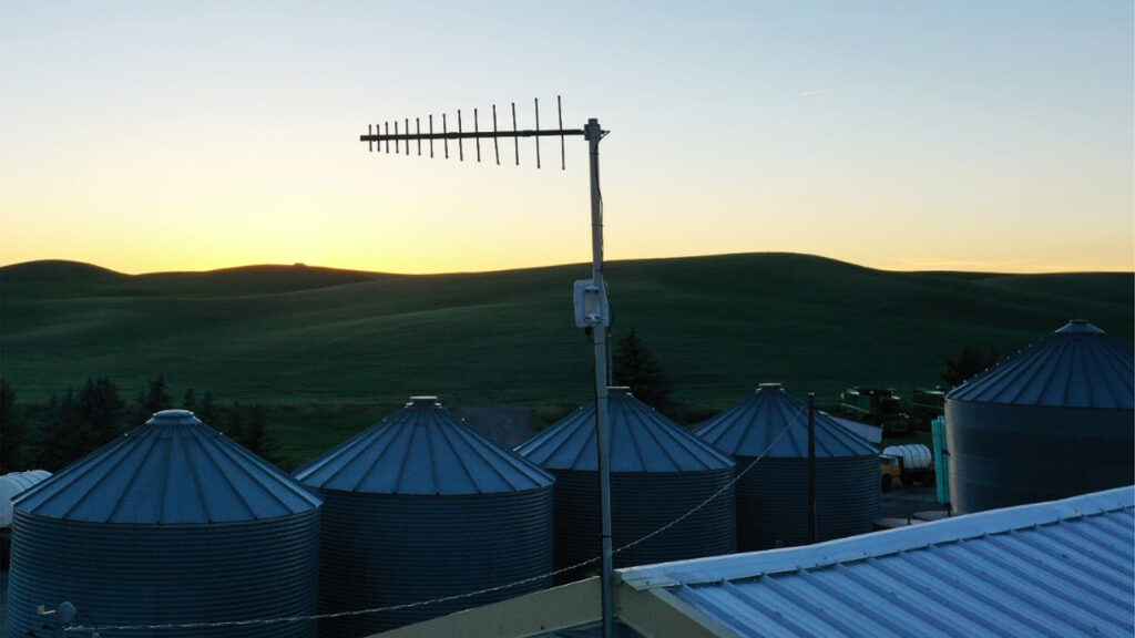 FarmVibes - photo of silos and an antenna against a sunset sky