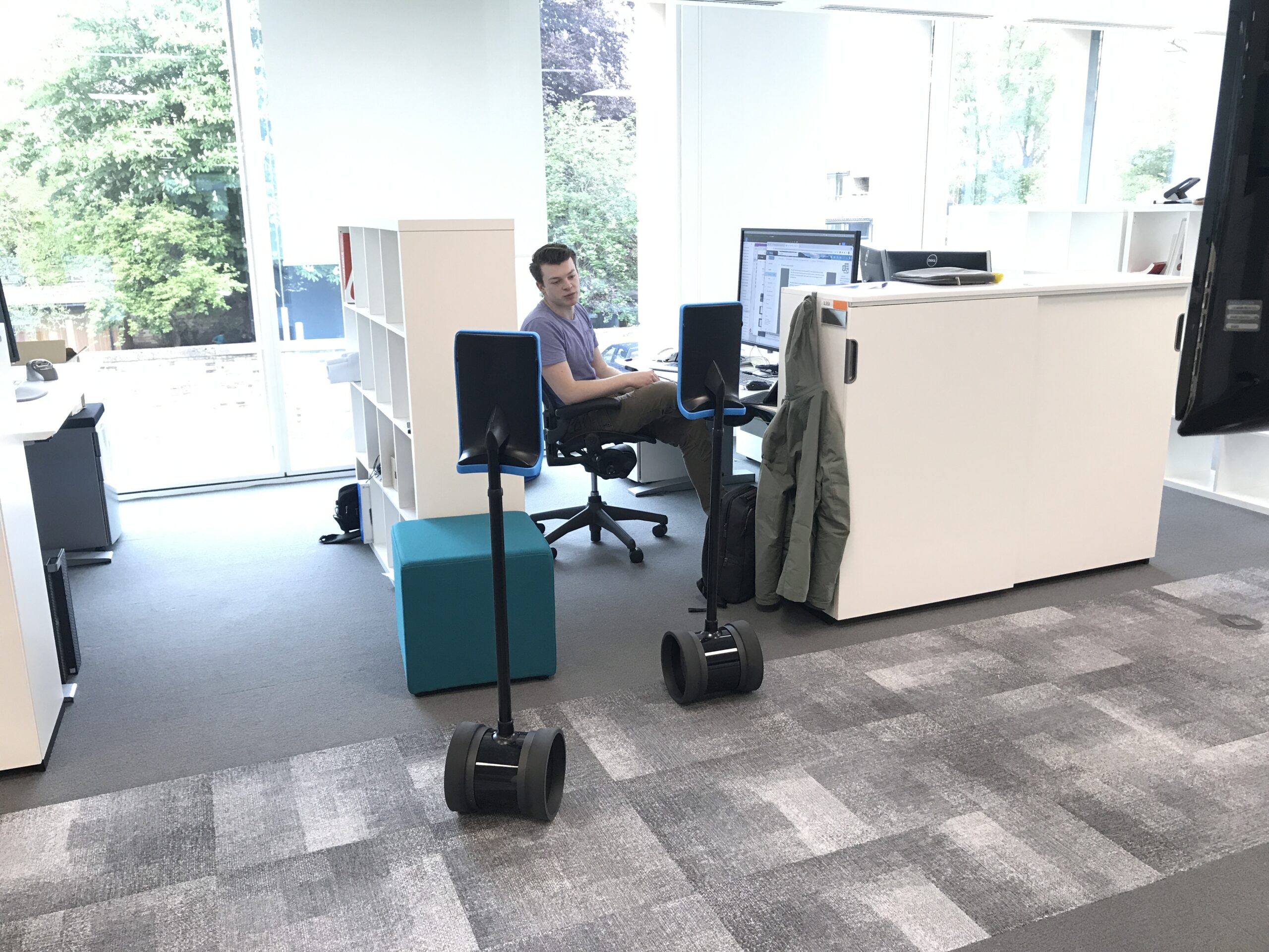A man talks to people in two telepresence robots in an office
