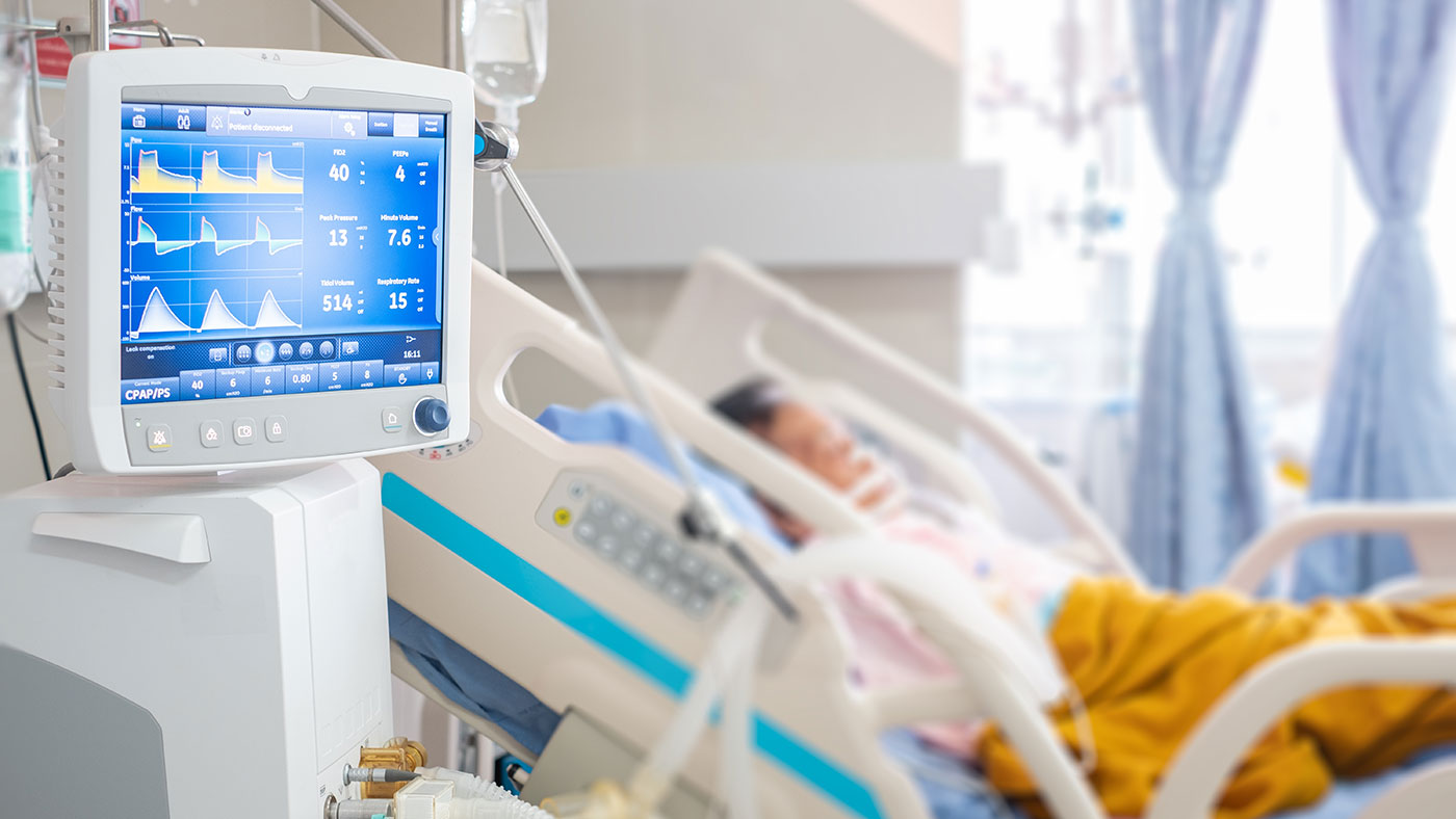 a CPAP/PS machine hooked up to a patient out of focus in the background