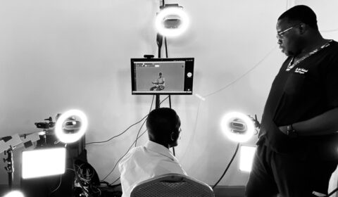 A picture captured at the Telemedicine rig in Accra depicting a male black patient seated inside the rig, with multiple Azure Kinect cameras positioned around him. He is engaged in a conversation with a doctor standing beside him.