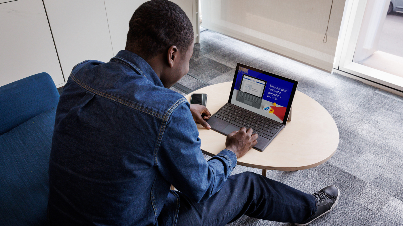 black male sitting at a table working on a laptop