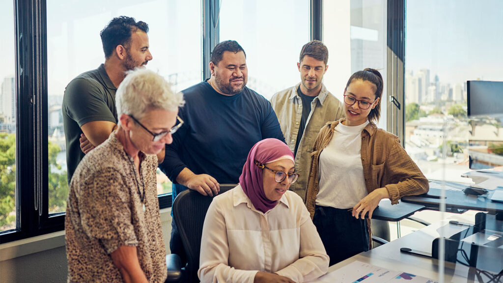 AI for Good - a diverse group of six people gathered around a desk reviewing a project