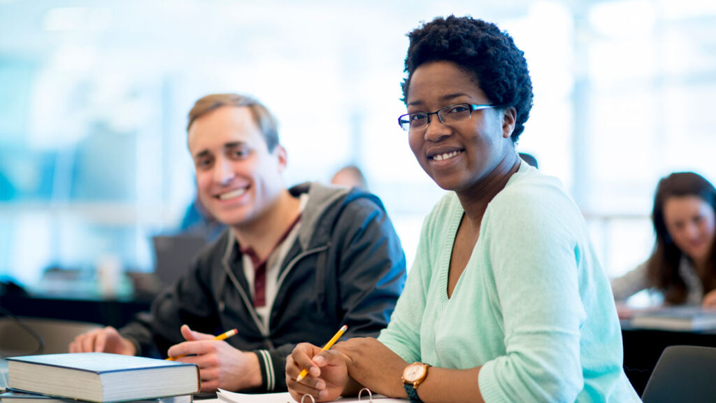 AI4Good - Expand Opportunity | two people sitting at a desk and looking at the camera