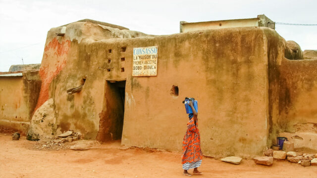 woman in front of mud hut