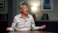 Peter Lee sitting at a table having a discussion with Vijay Mital and Gretchen Huizinga