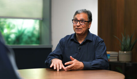 Vijay Mital sitting at a table having a discussion with Peter Lee and Gretchen Huizinga