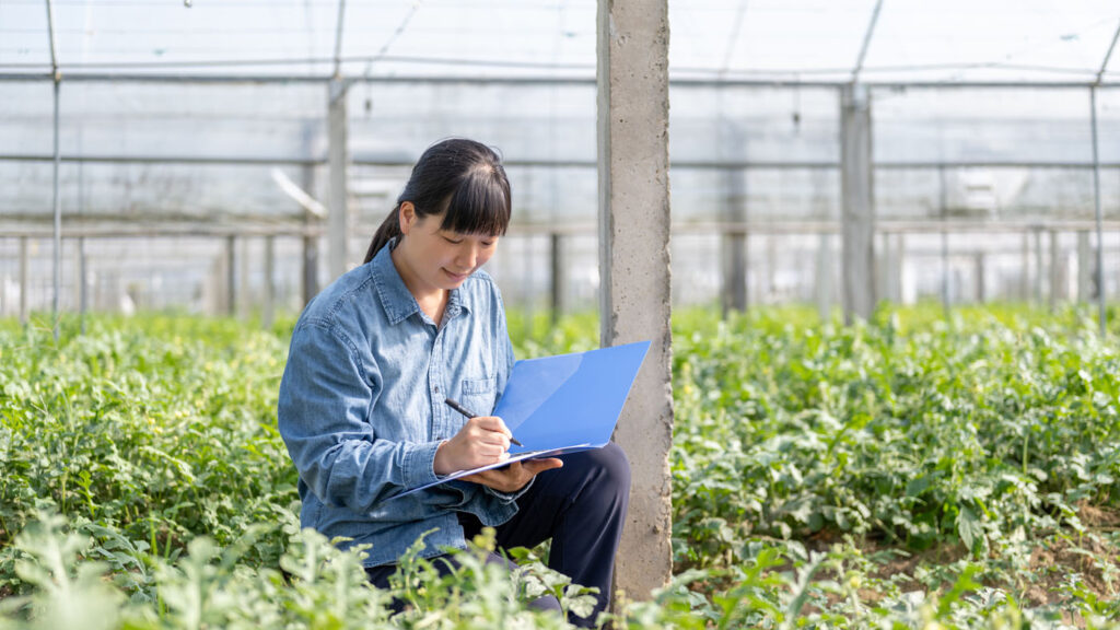 AI4Good - Expand Opportunity | woman taking notes in a greenhouse