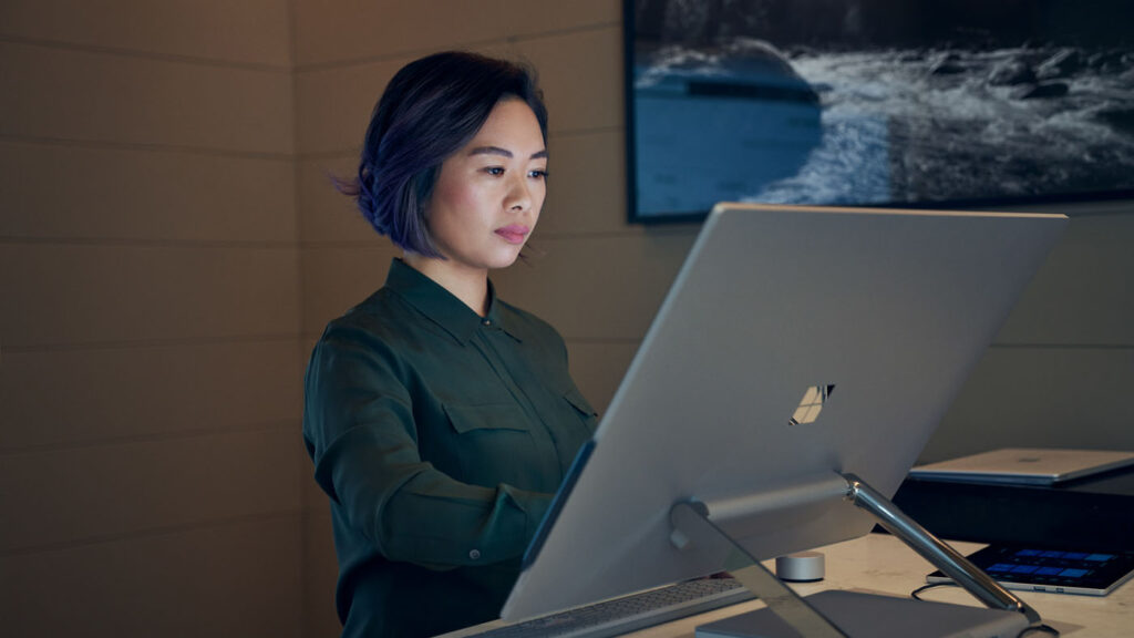 Woman standing in front of a large screen monitor and surface hub