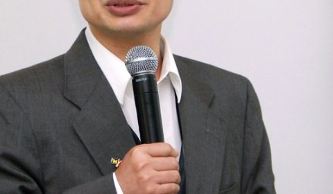 a man wearing a suit and tie holding a microphone