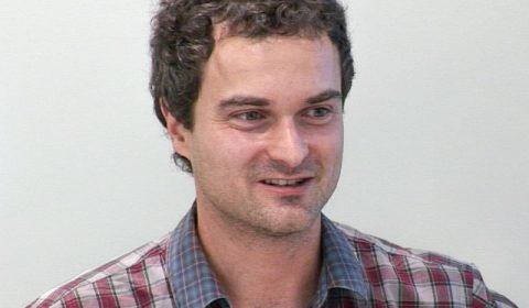 a man wearing a striped shirt and looking at the camera