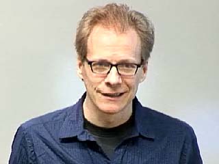 William Cook wearing glasses and smiling at the camera