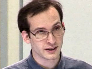 a man wearing glasses and smiling at the camera