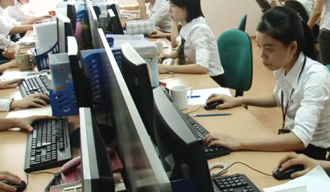 a group of people sitting at a table using a laptop computer