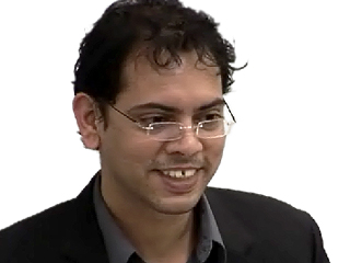 a man wearing glasses and smiling at the camera