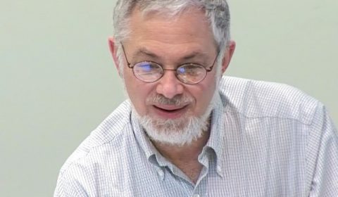 a man wearing glasses and smiling at the camera