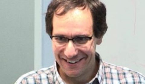 a man wearing glasses and smiling at the camera