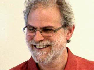 Philip Wadler wearing glasses and smiling at the camera